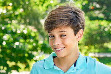 Handsome fervent smiling teenager, portrait on green garden background
