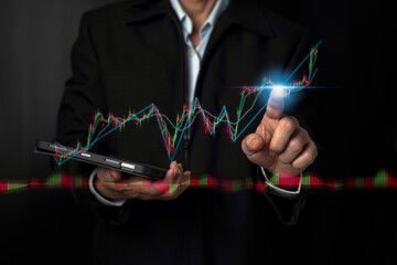Fototapeta premium Businessman or trader is holding tablet and another pointing a growing virtual hologram stock, invest in trading. Planning analyze indicator and strategy buy and sell, Stock market, Business growth.