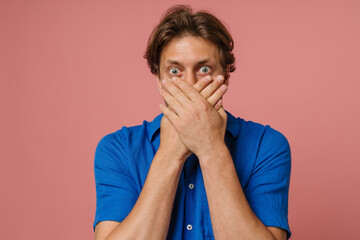 Shocked man covering his mouth isolated over pink wall