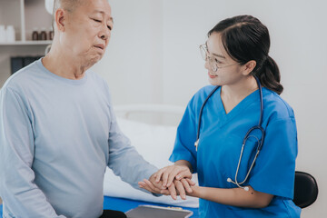 Beautiful Asian female nurse in a nursing uniform talks to a senior patient at the bedside in a hospital or clinic department.