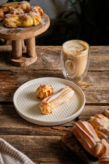 Homemade Eclairs and profiteroles with powdered sugar. Side view, wooden background.
