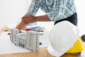 architect is preparing house model and construction plans on blueprints for construction...