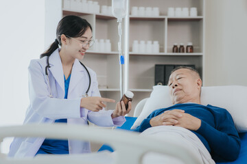 Beautiful Asian female doctor in white top talking with senior patient at bedside in hospital or clinic ward