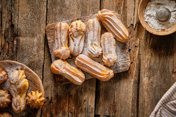 Homemade Eclairs with powdered sugar. Top view, wooden background.
