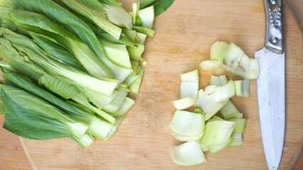 Pile of cut leafy mustard greens on wooden cutting board table background. the results of cutting mustard greens using a stenlis knife. stock photo
