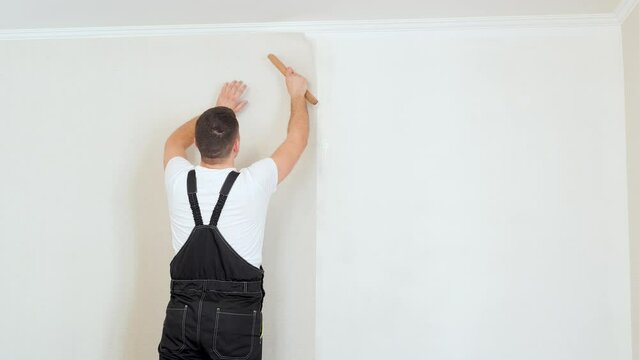 Man glueing wallpapers at home, stylish wallpaper sheet. Space for text