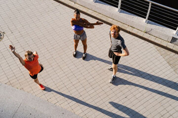 Top view group of three fitness people doing workout together outdoors on bridge