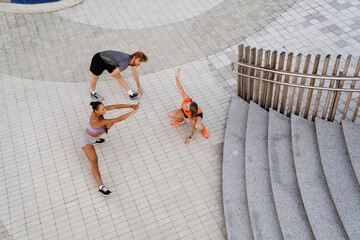 Top view group of three multinational people doing workout together outdoors