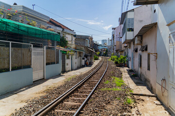 Fototapeta na wymiar Street - railway. A small street in Nha Trang in Vietnam with railway tracks running through the residential sector.