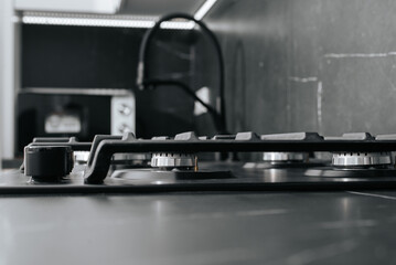 Modern new gas hob installed in dark kitchen countertops. Low angle view, selective focus