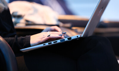 Close up view with a woman hands with long black nails while writes on a laptop during work from home.