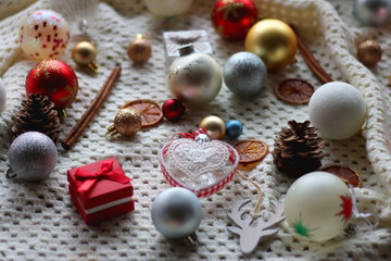 Fototapeta na wymiar Various colorful Christmas ornaments, small presents and seasonal spices on white knitted blanket. Selective focus.