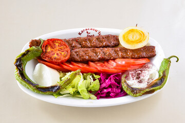 Grilled Turkish Adana, Urfa  Kebab with grilled vegetables, onion and rice on plate. Adana durum.