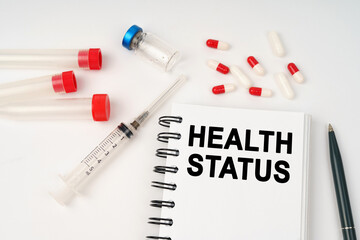 On the table are pills, injections, a syringe and a notepad with the inscription - Health Status