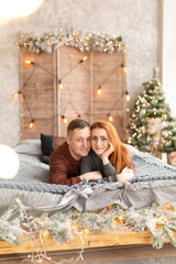 portrait of a couple on the bed near the New Year tree. the winter vacation. Christmas morning family celebrations