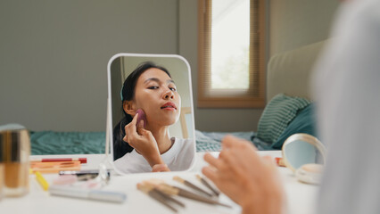 Young Asia girl beauty blogger, look at the mirror, makeup use sponge apply foundation on her face...