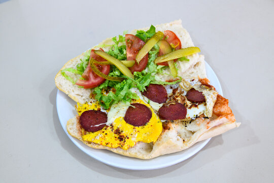 Close-up shot of Izmir's famous Turkish Traditional Kumru Sandwich, Ceşme Kumru, patso ingredients ready to eat salami, soudjouk, tomato, cheddar cheese and fried cheese. Yengen sandvic.