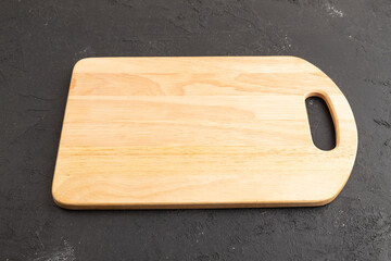 Empty rectangular wooden cutting board on black concrete. Side view