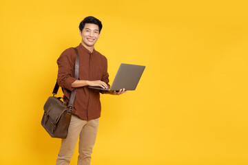 Young Asian businessman with laptop computer and brown leather bag isolated on yellow background