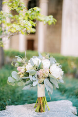 Bouquet of flowers stands on an antique stone pedestal in the garden