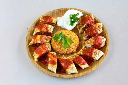 Turkish and Arabic Traditional Ramadan doner kebab with tasty tomato sauce and rice or turkish pilav in white plate on wood table background. ( Pilav ustu et doner, Hatay tavuk doner iskender kebap )