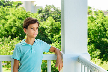 Portrait of a handsome thoughtful teenager looking afar on green garden background