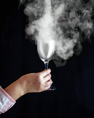 The wine glass in the hand is filled with smoke