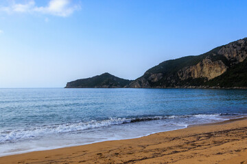 Sandy beach by the sea near Agios Georgios on the island of Corfu under a blue sky