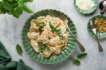 Homemade italian ravioli pasta in heart shape with beef meat, cheese butter sauce, caramelized onions, basil and saffron on old grey background. Food cooking menu ingredients background. Top view.