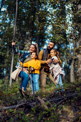 Fototapeta premium Smiling family of four exploring nature while hiking in forest.