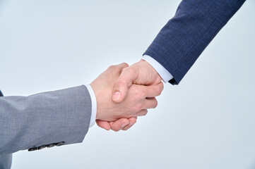 Two men in suits are shaking hands.