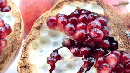 closeup of a broken pomegranate with its red seeds, on a white background
