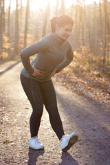 Beautiful sporty athletic young woman doing stretching exercises in forest on a cold sunny morning...