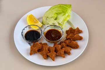 Cig kofte (raw meatball) with lettuce, tomato, pickle and lemon, hot Chee kofta. Turkish local raw food concept.Table scene of assorted take out or delivery foods. Doritoslu cig kofte durum.