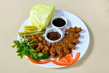 Cig kofte (raw meatball) with lettuce, tomato, pickle and lemon, hot Chee kofta. Turkish local raw food concept.Table scene of assorted take out or delivery foods. Doritoslu cig kofte durum.