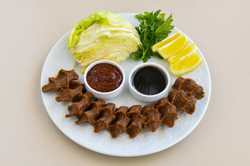 Cig kofte (raw meatball) with lettuce, tomato, pickle and lemon, hot Chee kofta. Turkish local raw food concept.Table scene of assorted take out or delivery foods. Doritoslu cig kofte durum.