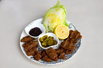 Cig kofte (raw meatball) with lettuce, tomato, pickle and lemon, hot Chee kofta. Turkish local raw food concept.Table scene of assorted take out or delivery foods. Doritoslu cig kofte durum.