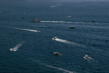 Amalfi Sea Coast with Umbrellas, people swim, and Yachts. Clean and blue sea where to swim. Photo for tourism and summer background. Concept of vacation and beach life in the open air  