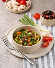 plate with stewed vegetables, next to green onions and a plate with tomatoes and mushrooms, gray background,  close-up