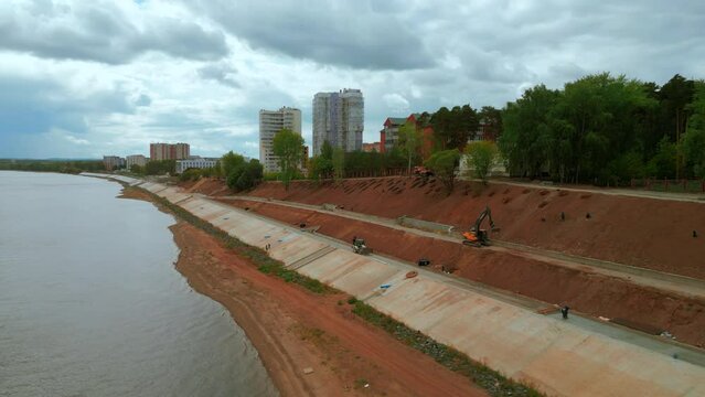 Construction and strengthening of a new safety embankment along the river. Clip. Aerial view ov the improving city area.