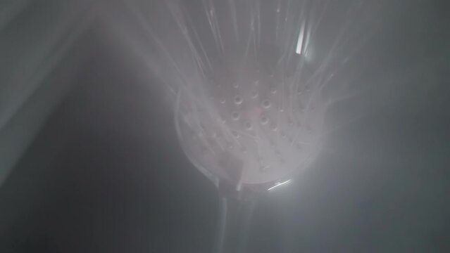 Water pouring down from massage shower head in bathroom. Liquid sprays and steam for body washing in home washroom bottom view. Sanitary equipment