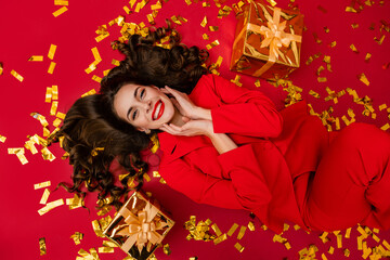 attractive woman celebrating Christmas on red background in confetti