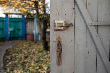 trying a rusty lock door in the background of a village yard with a green gate