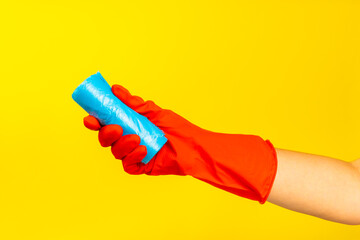 Woman's hands holding a garbage bag on a colored background. roll with plastic bags for garbage on background. Place for text. Garbage sorting.