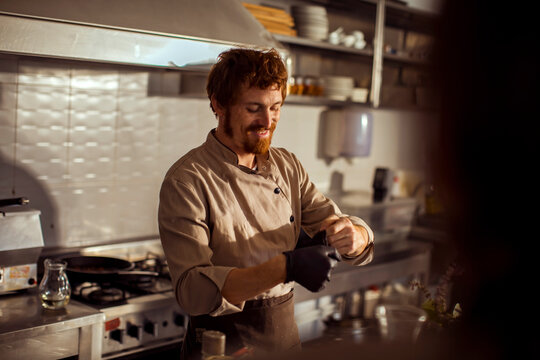 Naklejki Smiling chef preparing food in professional kitchen