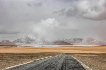 Zelfklevend Fotobehang Ali region of Tibet with a winding road, vast mountains, and sprawling fields © Wirestock