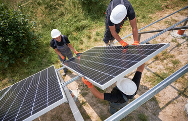 Male workers installing photovoltaic solar panel system outdoors. Men engineers placing solar...