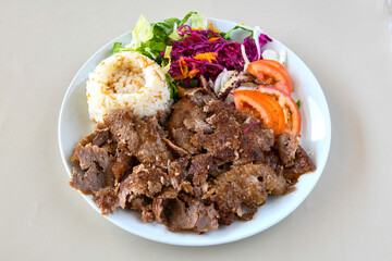 Turkish and Arabic Traditional Ramadan doner kebab with tasty tomato sauce and rice or turkish pilav in white plate on wood table background. ( Pilav ustu et doner, Hatay tavuk doner iskender kebap )