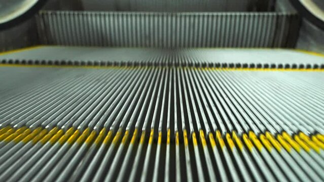 Close up of the fast moving down empty escalator steps with grooves.