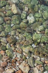 clear sea water flowing ober green stones on the Mediterranean coast relaxing water background